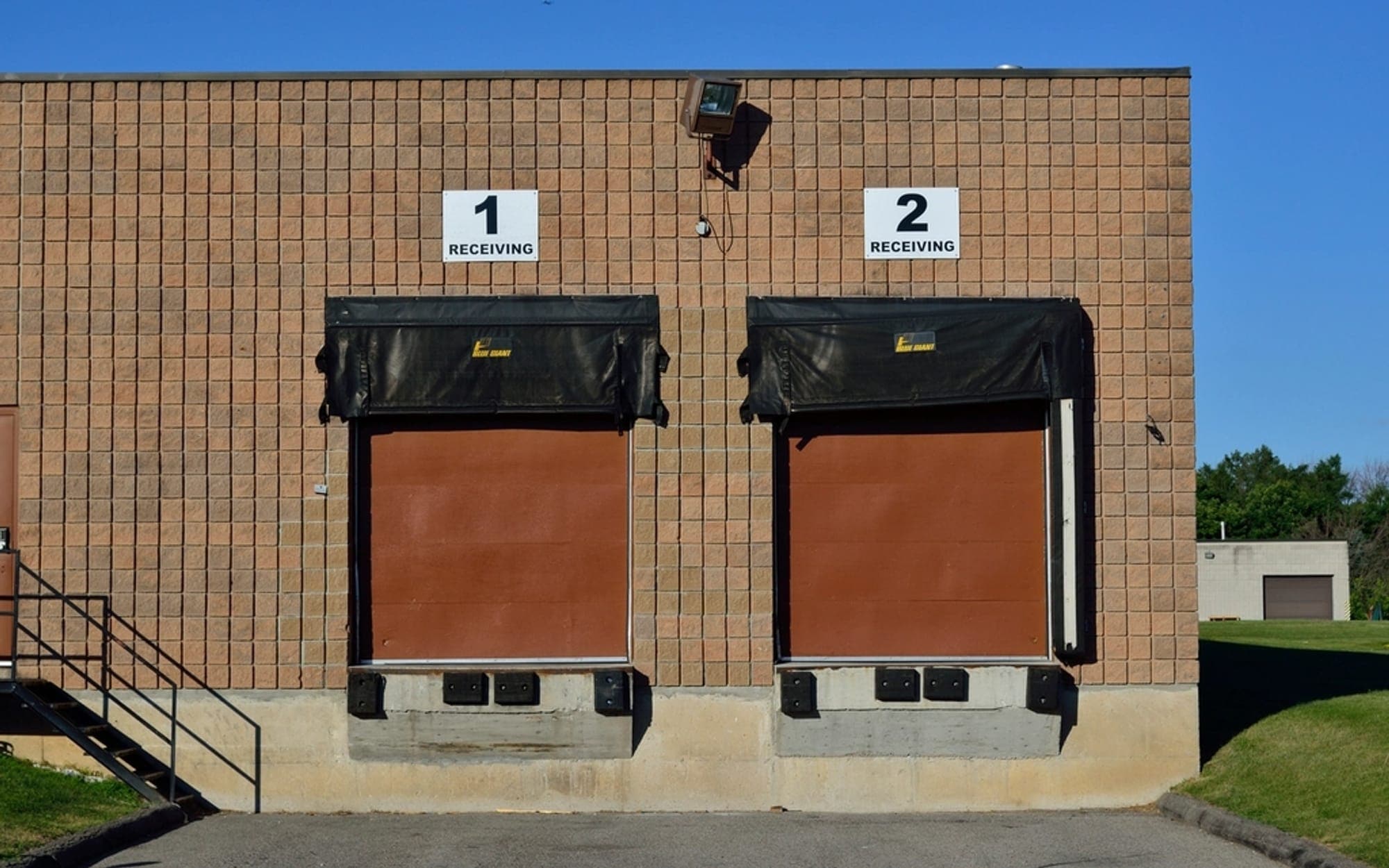 Two numbered loading dock doors on a brick warehouse building