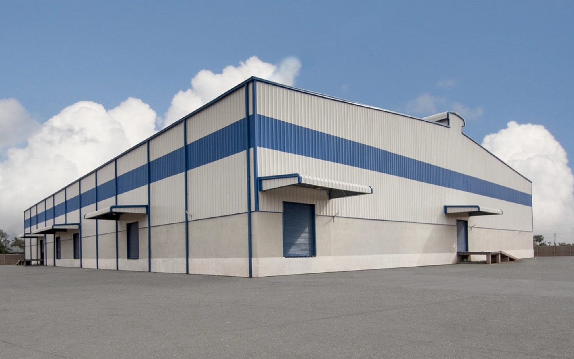 Exterior of a modern industrial warehouse building under a cloudy sky