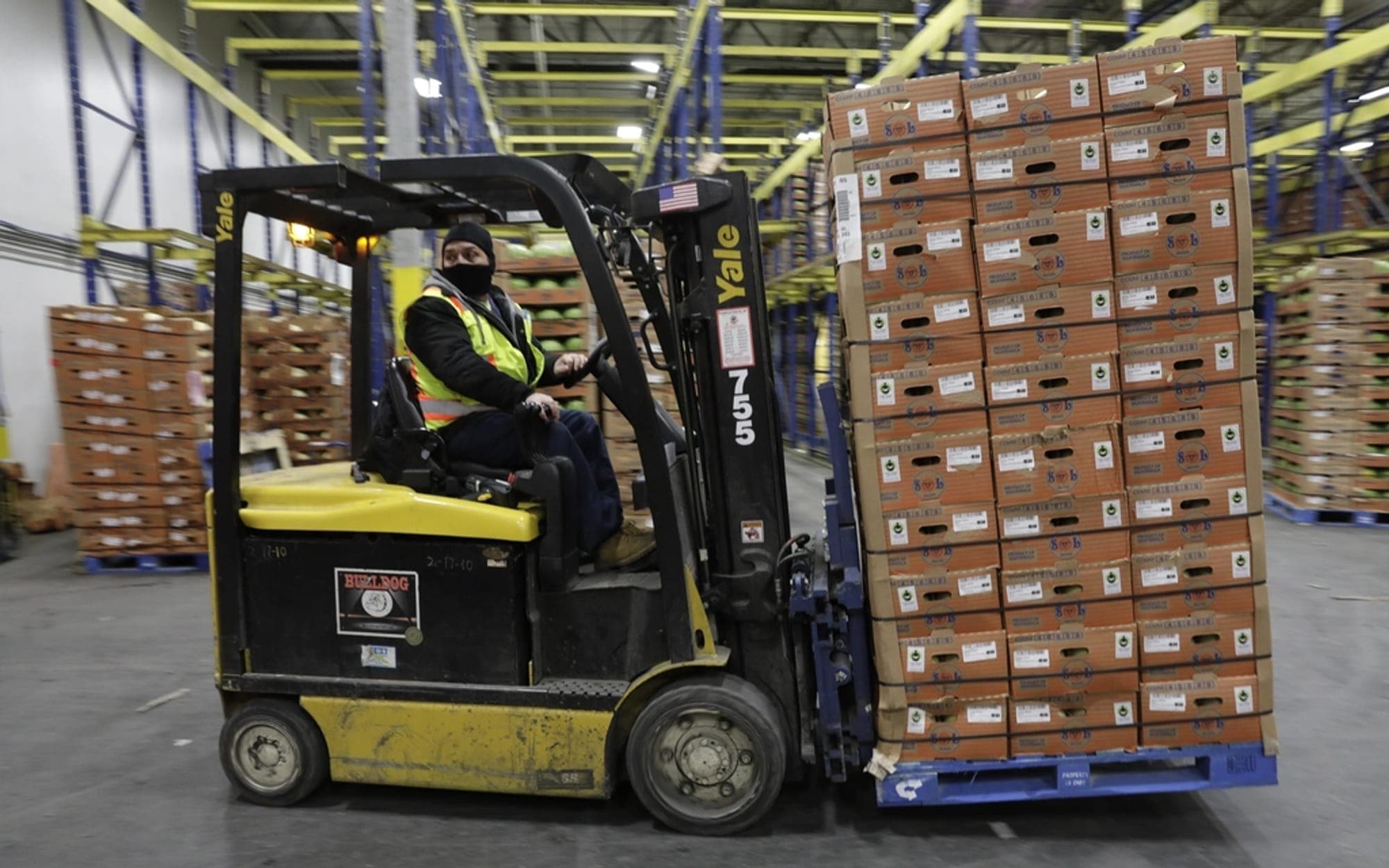 Forklift carrying a stack of cartons through a warehouse