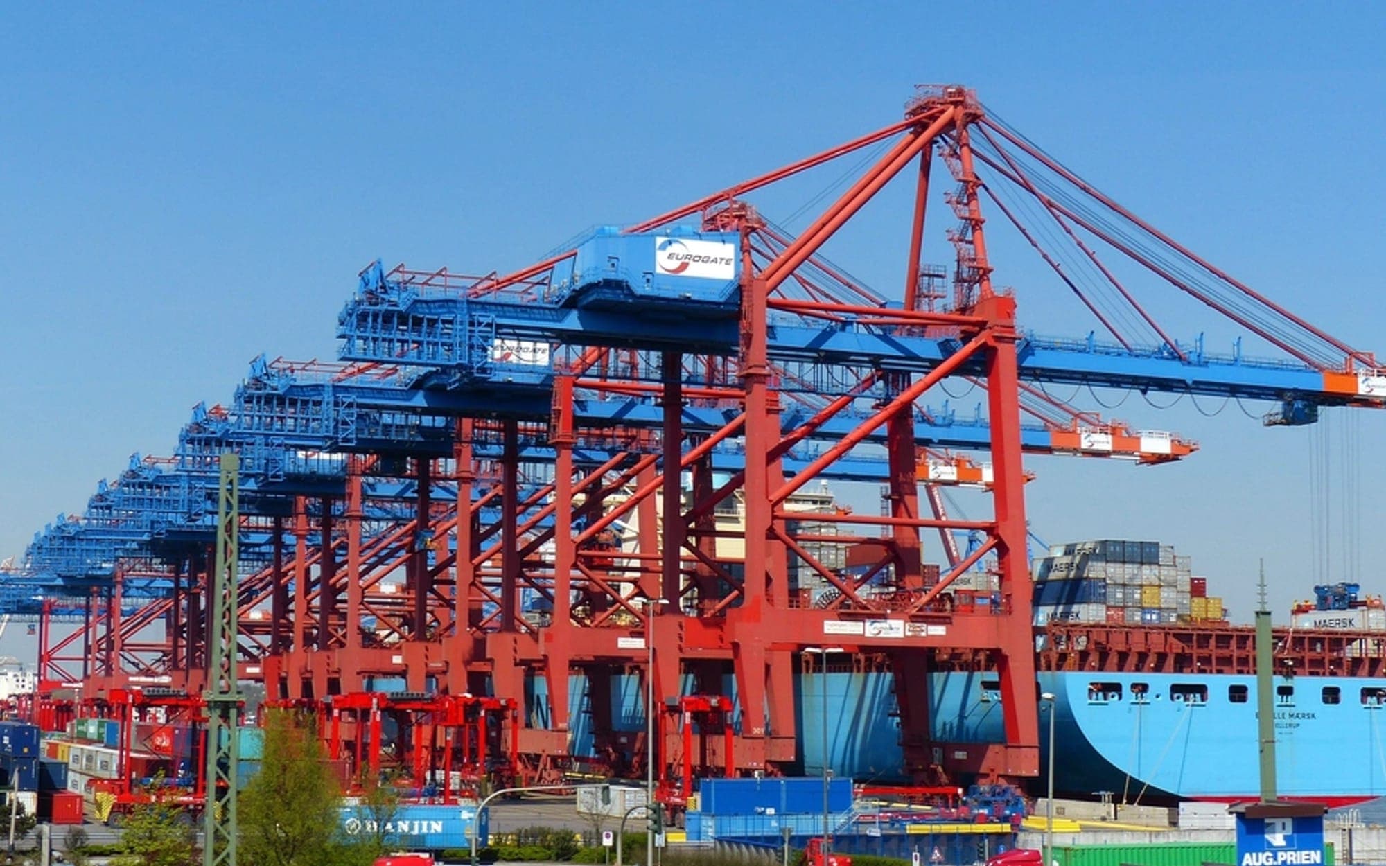 Red gantry cranes and a container ship at a port terminal