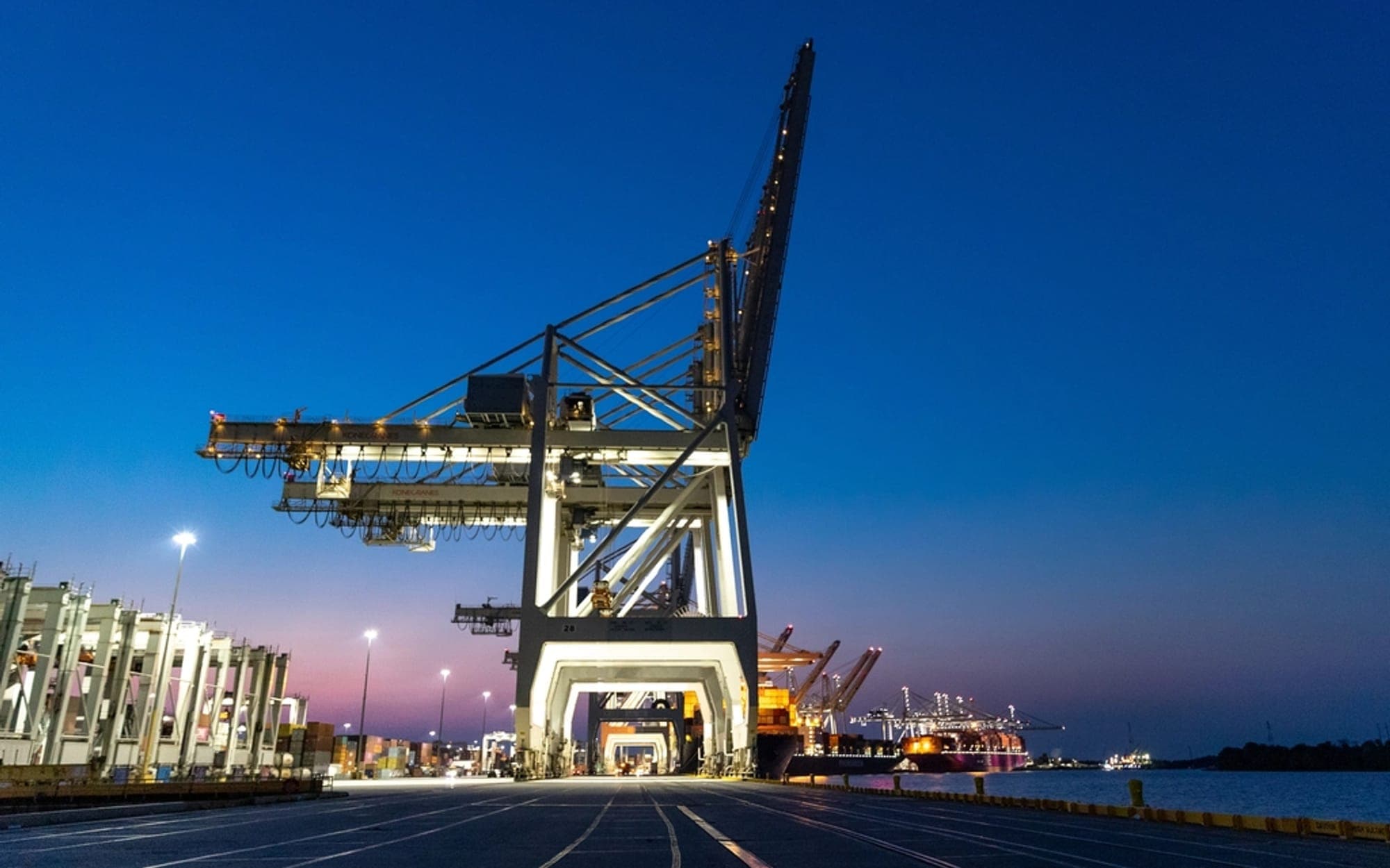 Port gantry cranes standing over a container terminal at dusk