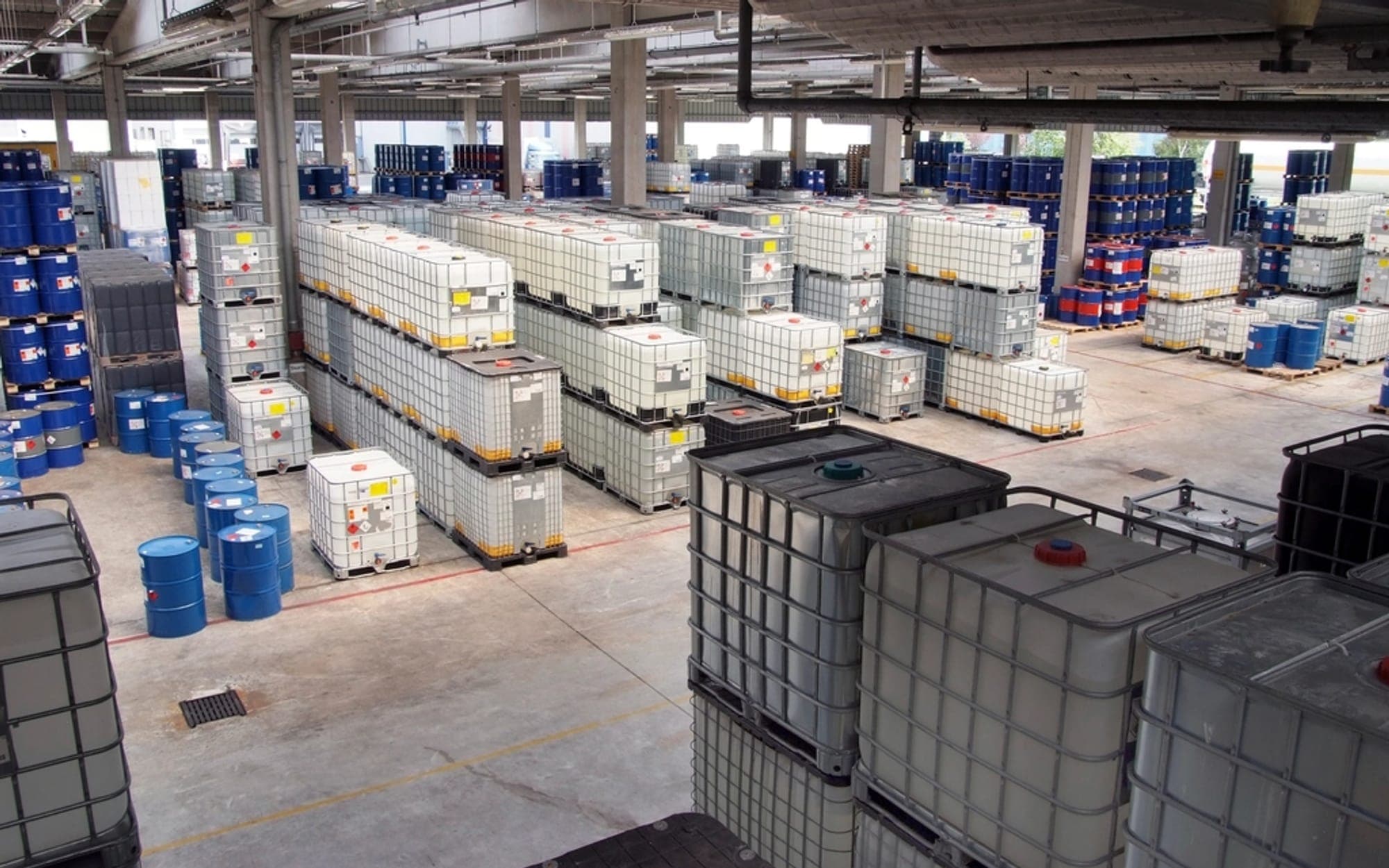 Warehouse floor stacked with intermediate bulk containers and drums